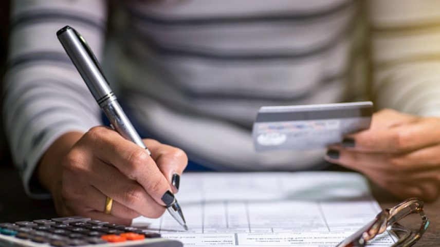 Imagem colorida mostra pessoa fazendo contas com uma calculadora e segurando cartão desenrola brasil - Metrópoles