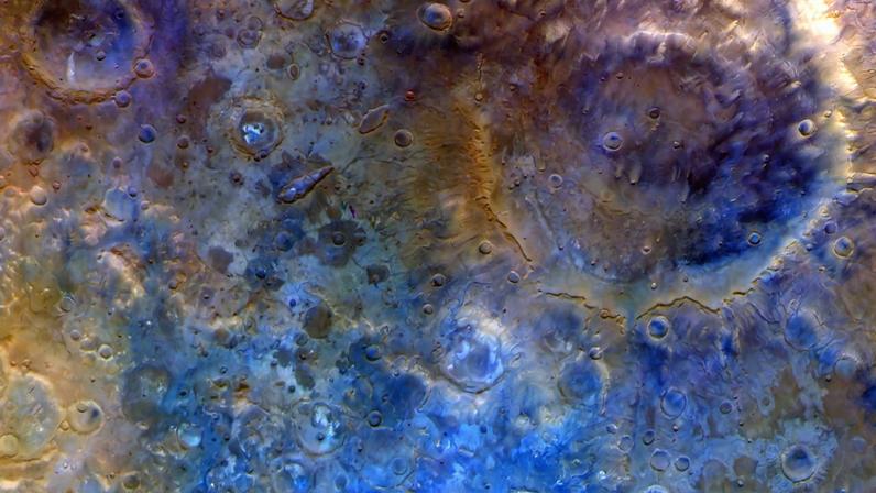 In this representative color image, Mars' surface appears in shades of red, orange, and blue. At right is a double-ring crater called Huygens. To