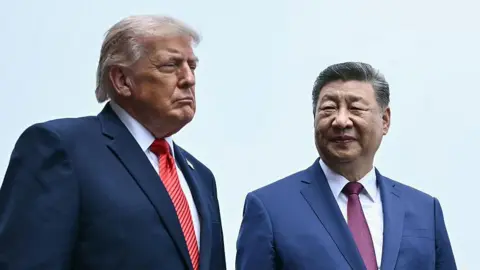 Getty Images US President Donald Trump and China's President Xi Jinping walk side by side on a visit of the Temple of Heaven in Beijing on May 14 2026. Both men are wearing blue suits. Trump is wearing a red striped tie, while Xi is wearing a purple one. Both men have serious expressions