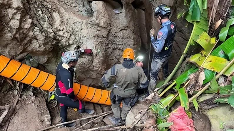 Reuters Four rescuers wearing helmets stand at the entrance to a cave