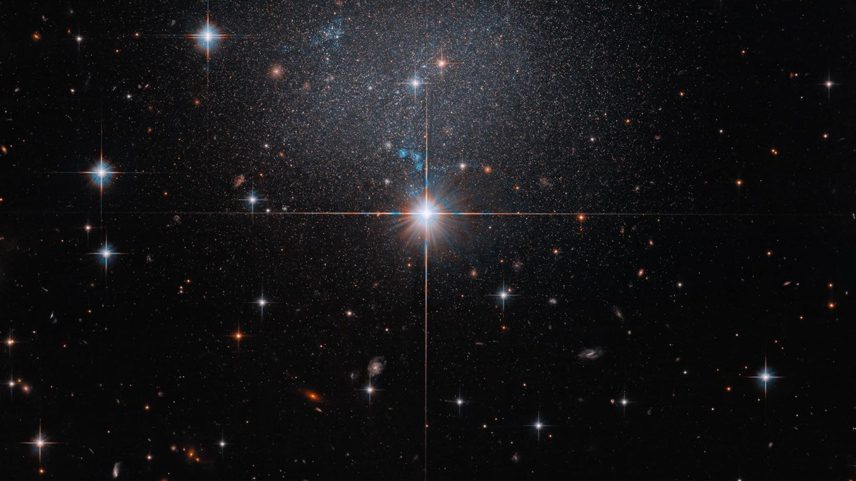 This NASA Hubble Space Telescope image captures the faint glow of the dwarf irregular galaxy ESO 490-017.