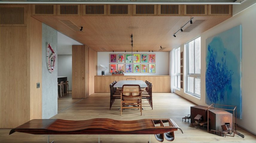 INTEGRAÇÃO | A base neutra do ambiente dá destaque ao mobiliário brasileiro, com mesa de Jader Almeida e cadeiras de Sergio Rodrigues, parte do acervo dos moradores. O banco Ondas, de Jorge Zalszupin, divide a sala de jantar do living. Ao lado, à direita, no chão, a obra Duas Cabeças, de José Bechara e, na parede, o quadro de Pedro Varela. Do lado esquerdo, obra de Lucas Dupin e , ao fundo, conjunto de quadros de Duda Moraes. A marcenaria em carvalho-americano foi executada pela AG Movelaria e Design, e o projeto de iluminação é do Auma Studio