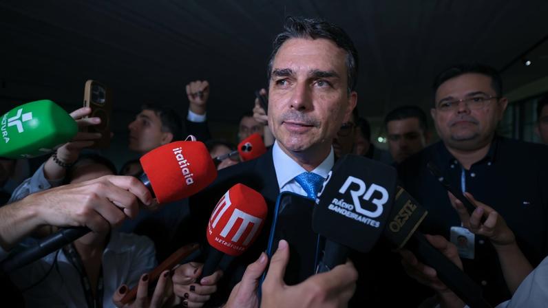 Flávio Bolsonaro cercado de microfones