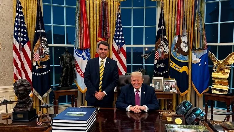 Flávio em pé ao lado do presidente norte-americano, Donald Trump, no Salão Oval