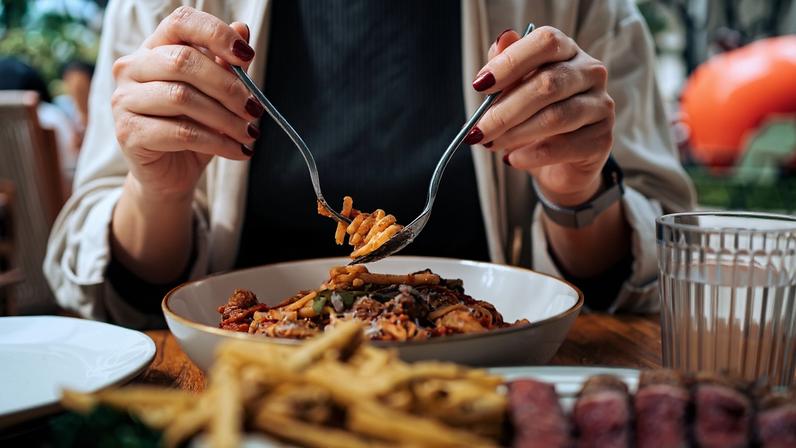 Foto colorida de mulher comendo - Sente mais fome que o comum? Saiba o que acontece com o seu corpo - Metrópoles