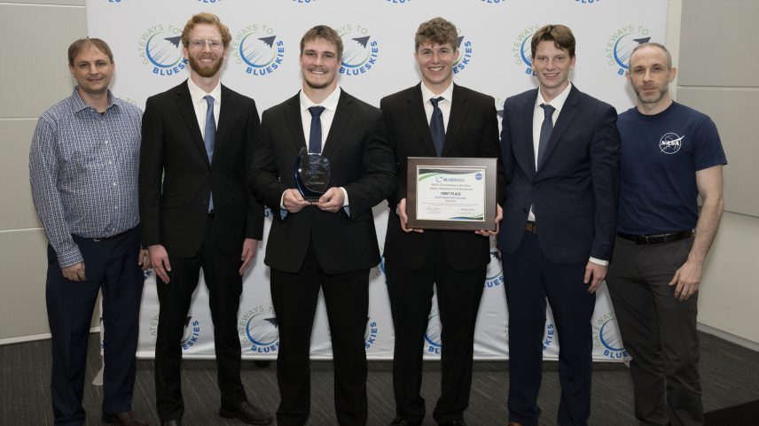 The members of team WINGMAN stand in the center of the photo holding their first place certificate for NASA's Gateways to Blue Skies Competition.