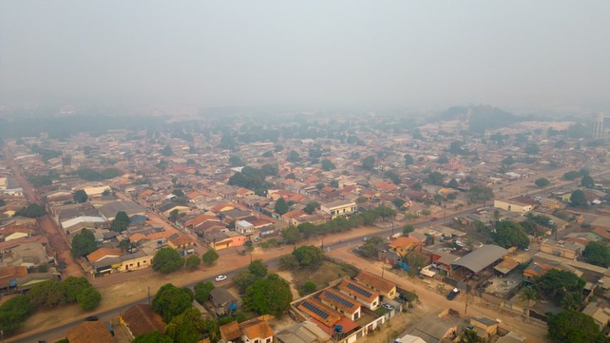 Vista aérea de Santarém, cidade do Pará, encoberta por fumaça de queimadas durante a seca amazônica de 2023; crise climática, com degradação ambiental, amplia deslocamentos climáticos no Brasil.