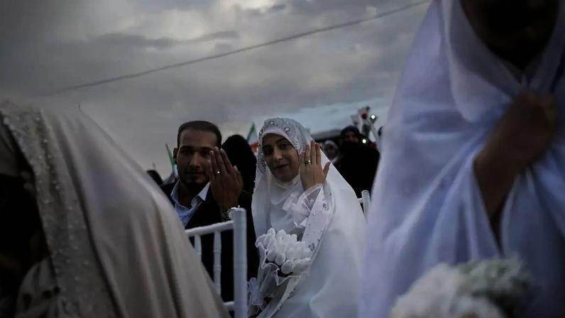 Um casal exibe suas alianças durante uma cerimônia de casamento em massa para Casais Abnegados, organizada pela Guarda Revolucionária Islâmica.