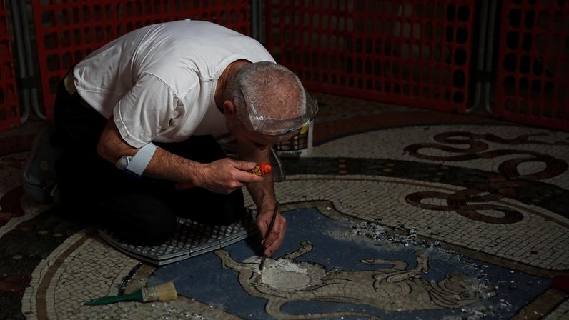 Um operário restaura os testículos do mosaico do touro no centro da Galleria Vittorio Emanuele II na Itália