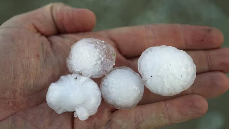 Pessoa segura diversas pedras de granizo na mão — Foto: Getty Images
