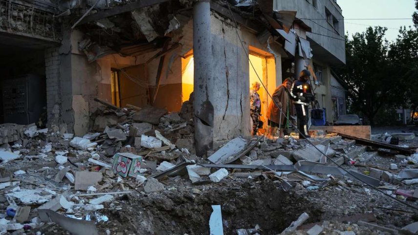 Uma idosa caminha com a ajuda de um socorrista em meio aos escombros de um prédio residencial danificado após um ataque de drone russo em 12 de junho de 2025 em Kharkiv, Ucrânia.
