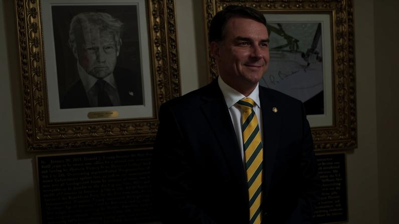 Flávio Bolsonaro ao lado de retrato de Donald Trump