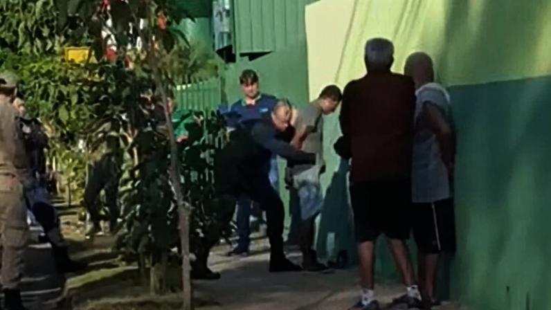 Imagem colorida, homem com faca domina e arrasta crianças em porta de escola- Metrópoles