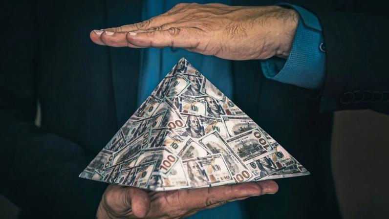 homem segura com duas mãos uma piramide de dinheiro