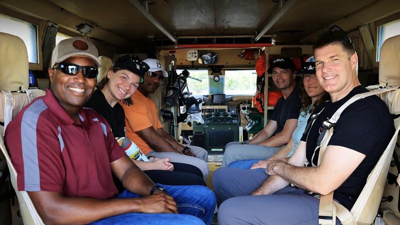 HWHAP Ep. 421. The Artemis II Crew, including backup crew members NASA astronaut Andre Douglas and Canadian Space Agency astronaut Jenni Gibbons, sit in the back of a transport van.