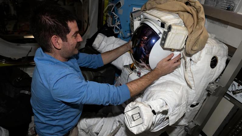 NASA astronaut and Expedition 74 flight engineer Jack Hathaway configures a spacesuit installing its components, checking a helmet, and cleaning suit seals inside the International Space Station's Quest airlock.