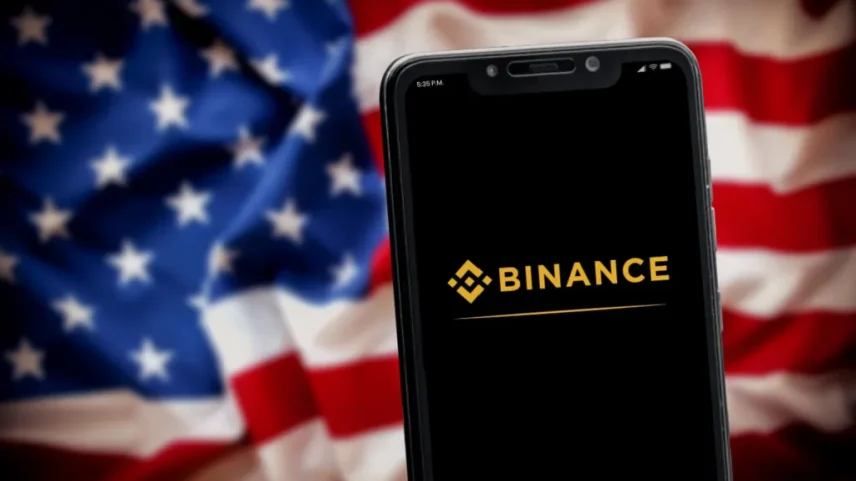 logo a binance no celular e bandeira dos EUA no fundo