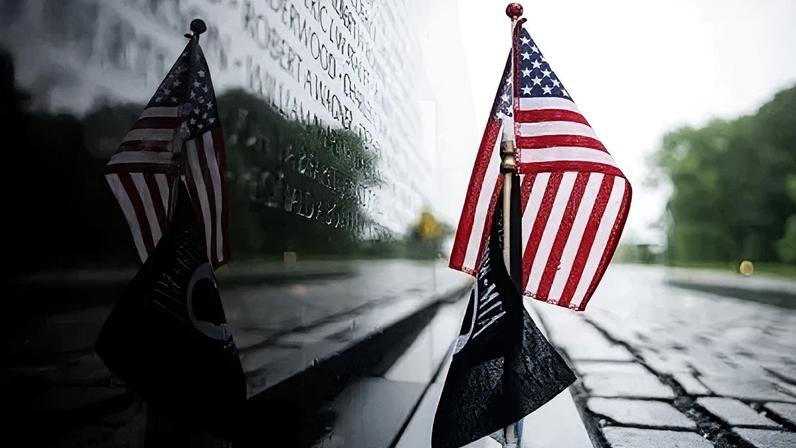 Bandeira dos Estados Unidos é colocada na base dos nomes gravados no granito preto do Memorial dos Veteranos do Vietnã, no Dia da Memória (Memorial DAy), em 25 de maio de 2026, em Washington, DC