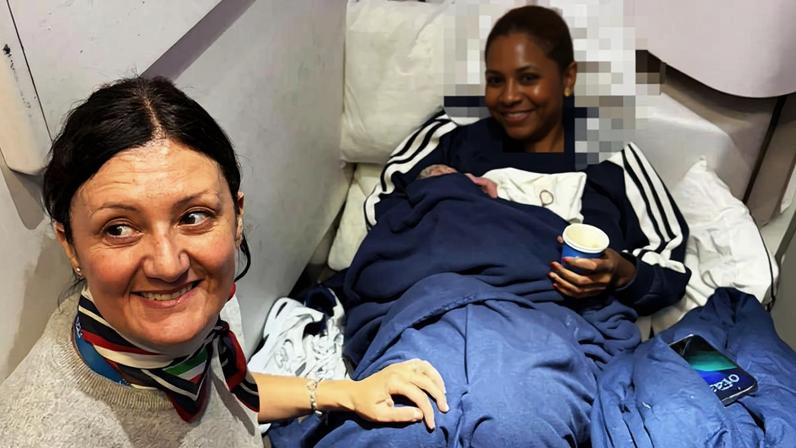 Foto colorida de uma mulher no avião dando à luz e uma funcionária