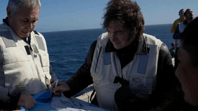 Javier Milei assina bandeira da Argentina durante visita ao porta-aviões USS Nimitz, em exercício militar com os Estados Unidos