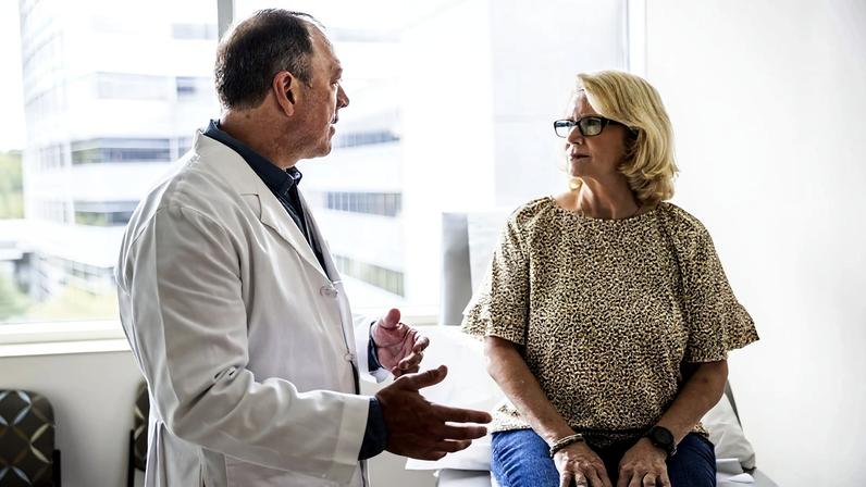 Médico sênior consultando uma mulher idosa na sala de exames - Diagnóstico com IA: entenda por que a supervisão médica é crucial