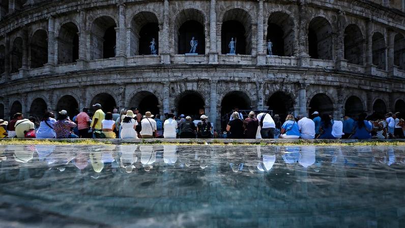 Pessoas sentam-se à sombra do Coliseu durante uma onda de calor no início da temporada em Roma