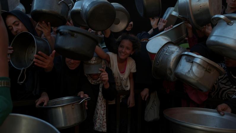 Palestinian women and children hold out their empty pots in front of a charity kitchen in Khan Yunis in the southern Gaza Strip on August 21, 2025. (Photo by AFP)