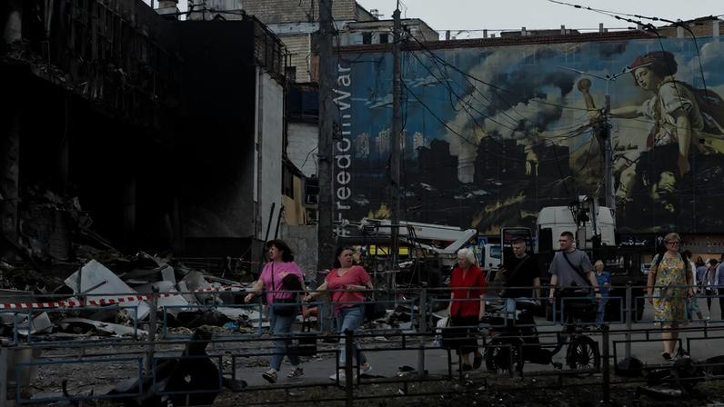 Moradores caminham ao lado de um shopping center danificado após ataques russos em Kiev