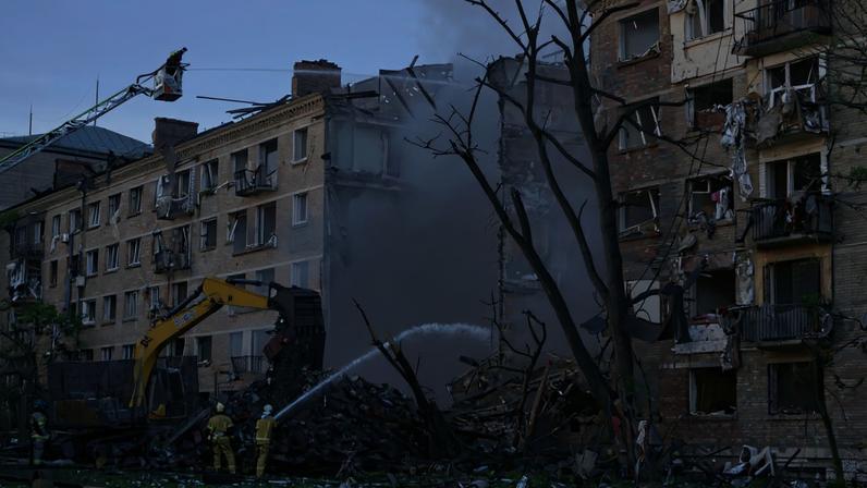 Bombeiros trabalham para extinguir um incêndio no local de um prédio gravemente danificado após ataques russos em Kiev, em 24 de maio de 2026
