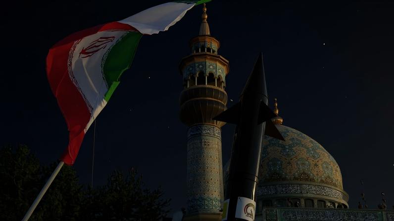 Iranianos levantam uma bandeira e a maquete de um míssil durante uma celebração após o ataque de mísseis e drones do Irã a Israel