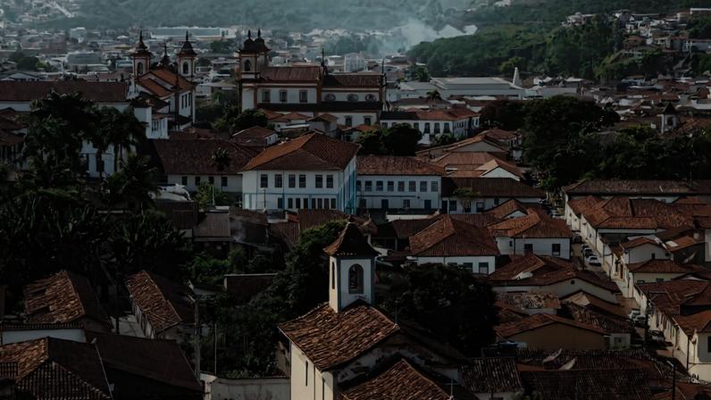 Vista panorâmica do centro histórico de Ouro Preto, com casario colonial e igrejas barrocas ao entardecer.