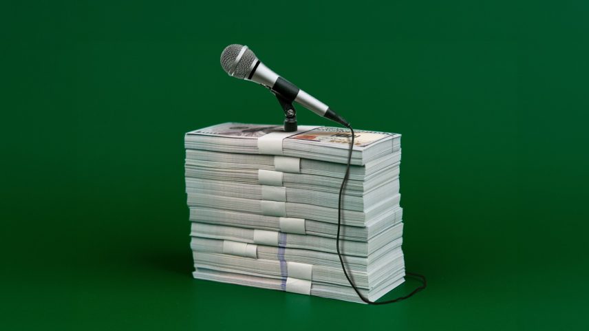 A stack of money used as a podium for a microphone.