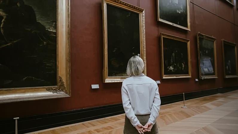 Mulher idosa observa telas em um museu