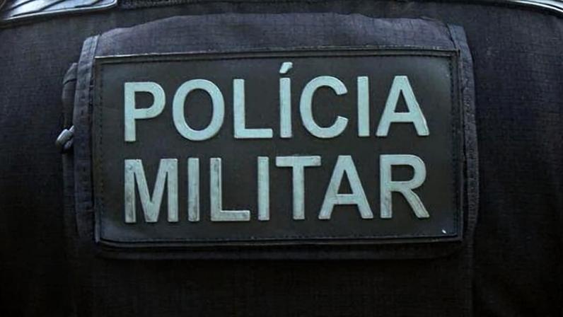 Foto colorida de um agente da Polícia Militar mostrando as costas do uniforme