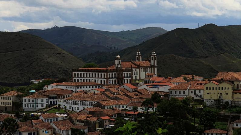 Vista urbana de Cachoeira de Minas, com montanhas ao fundo e céu claro