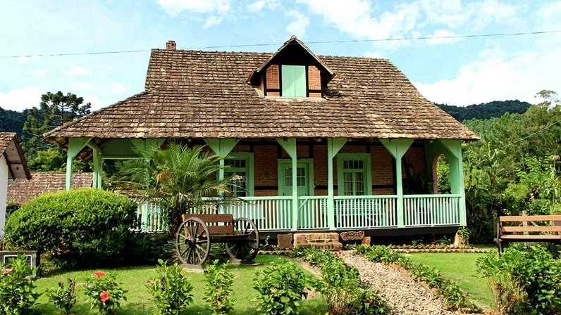 Casa em estilo colonial com jardins, representando o ambiente interiorano do Alto Vale do Itajaí. Crédito: Município de Dona Emma.