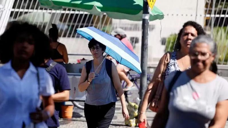 Mulher se protege do calor com um guarda-chuva. — Foto: © Tânia Rêgo/Agência Brasil