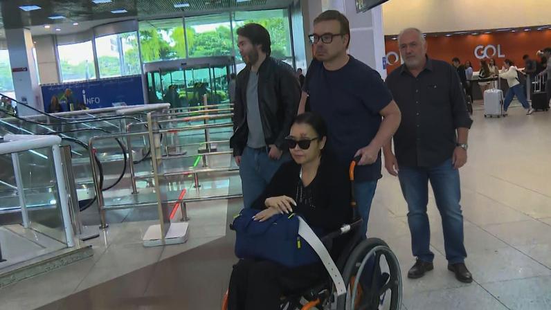 O diplomata Ibrahim Abdul Hak Neto empurra a cadeira de rodas da esposa, a também diplomata Ana Patrícia Neves Abdul Hak, no Aeroporto Santos Dumont — Foto: Betinho Casas Novas/ TV Globo