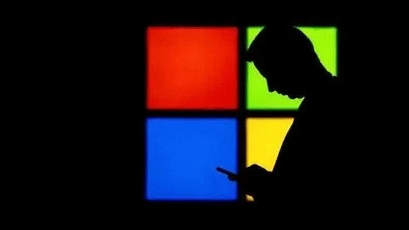 Um homem olha para seu telefone enquanto passa pelo estande da Microsoft na feira Mobile World Congress, em Barcelona, Espanha