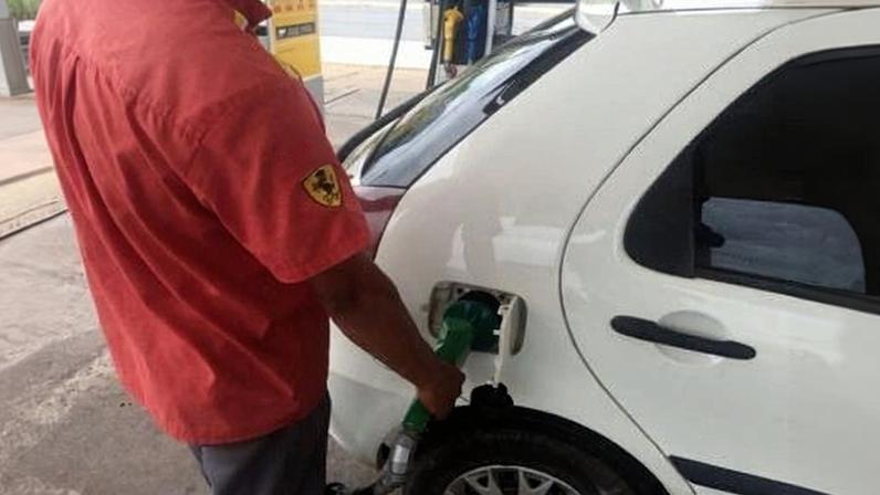 Funcionário de um posto de gasolina enche o tanque de um carro com etanol em Cuiabá