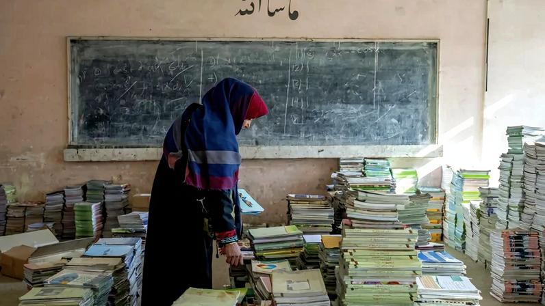 Professora recolhe livros em sala de aula destinada a mulheres em universidade no Afeganistão, após Talibã proibir acesso de universitárias às aulas.