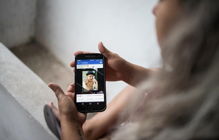Tatiana Lima e Silva segura celular com foto de seu filho Peterson Silva de Oliveira