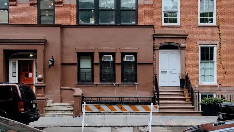 A street with an open parking spot blocked with an orange and white sign.