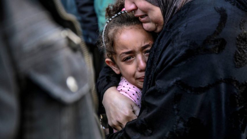Mulher palestina abraça criança após bombardeio israelense, em frente ao necrotério do hospital Al-Shifa, na cidade de Gaza