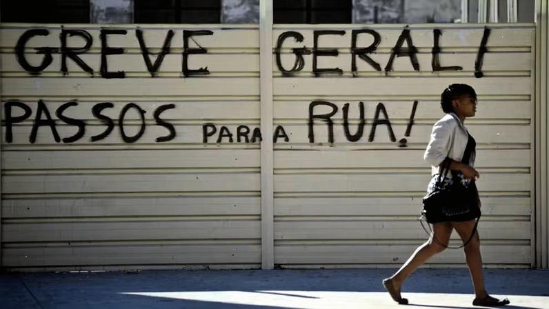 Mulher passa por pixação convocando greve em Lisboa, Portugal. — Foto: PATRICIA DE MELO MOREIRA/AFP