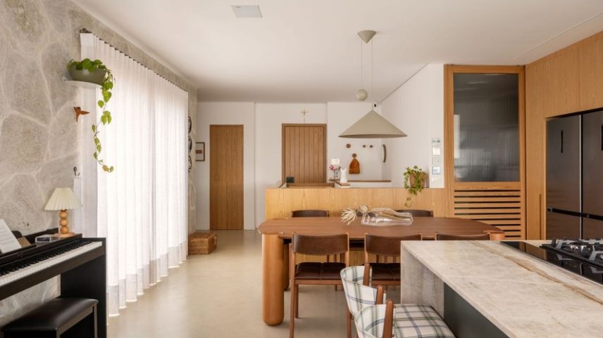 COZINHA INTEGRADA | No pavimento superior, a cozinha gourmet, em conexão com a sala de jantar e a varanda, é o coração do apartamento. A base do projeto foi construída com cores e materiais que remetem à natureza, como diferentes tons de azul e verde, além de elementos naturais, como o piso Mr. Skin Stone, da Protécnica, que remete a cimento queimado, além da pedra granito rústico mineiro amêndoa, da Art & Pedras, na parede onde está o piano, a qual se estende até a área da piscina na varanda