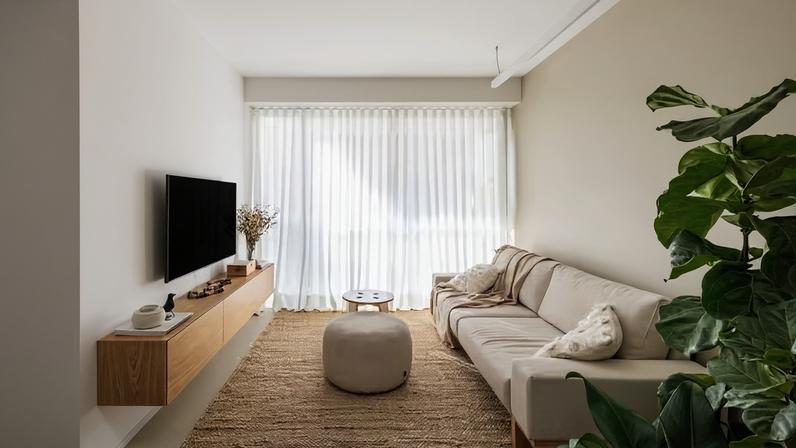 SALA DE ESTAR | A base neutra é aquecida por elementos naturais, como o tapete da by Kamy, as cortinas de linho Delínea, além do rack executado com acabamento de folha natural de carvalho americano por Unidos Decorações. Sofá e pufe assinados por Fernando Jaeger, enquanto a mesinha de centro, do acervo pessoal, foi feita pelo morador, o arquiteto Pedro Monfrinatti. Nos vasos de piso, ficus lyrata e pacová. Sobre o rack, dedo-de-anjo seco