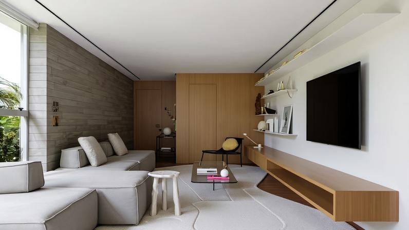 SALA DE ESTAR | A marcenaria em lâmina de madeira linheiro, com execução da Movip, contrasta com o revestimento da parede em ripas de concreto da RS Molduras, onde estão as obras da série Loading, de Livia Fontana. Sofá modular da marca Century, na Inove Design. Mesa de centro de vidro, de Giácomo Tomazzi, designer que também assina a poltrona Bo, na Boobam. Mesa de apoio Afinco, da Iludi Design, na Ornament Casa. Nas prateleiras, peças de acervo pessoal e afetivo do casal, como imagem de barro de São Francisco de Assis, pintura feita pela filha Celina, escultura de Amilcar de Castro e obra do artista eslovaco Albín Brunovský. Tapete orgânico personalizado da Originale Maison. No hall de entrada, carro-bar Linhas, de Hormigon, e cabideiro de parede Dorsal, de Tiago Curioni, ambos na Boobam