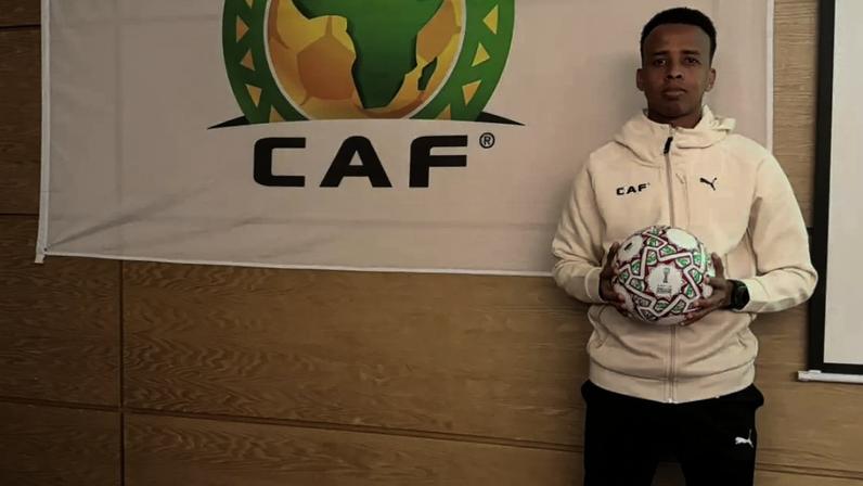 Omar Artan, árbitro da Somália, posa ao lado de bandeira da CAF