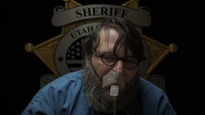 Nicholas Rossi, wearing an oxygen mask sitting in front of a Utah sheriff logo, speaks during a hearing livestreamed in January 2024, in Salt Lake City